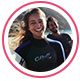 Profile image of reviewer, a young woman in wetsuit smiling on a windy beach.